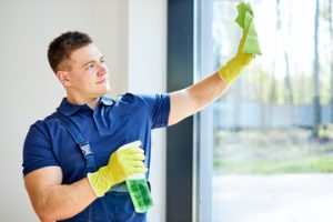 Professional cleaner wiping a window for a spotless finish. Ready to help with all your end-of-lease cleaning needs