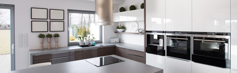 A clean kitchen with a sleek design, featuring black and white cabinetry, a stovetop, and stylish appliances. 