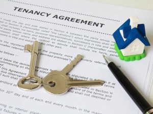 Tenancy agreement, keys, and a small house figure ready for the property handover.