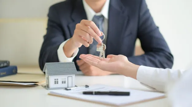 Is Bond Cleaning and End of Lease Cleaning Same? 3 real estate agent hands over the keys to a new tenant, completing the rental agreement process