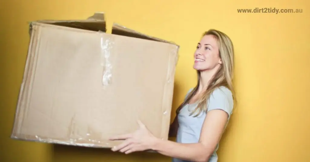8 Ways to Ensure Easy End of Lease Cleaning? 6 Woman carrying a large moving box with a smile.