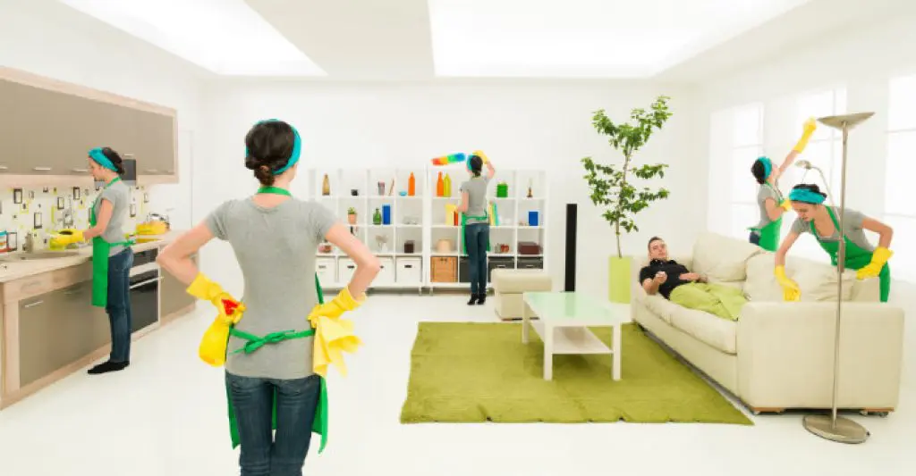  A professional end-of-lease cleaning team working efficiently in a modern living room while a tenant relaxes on the couch.

