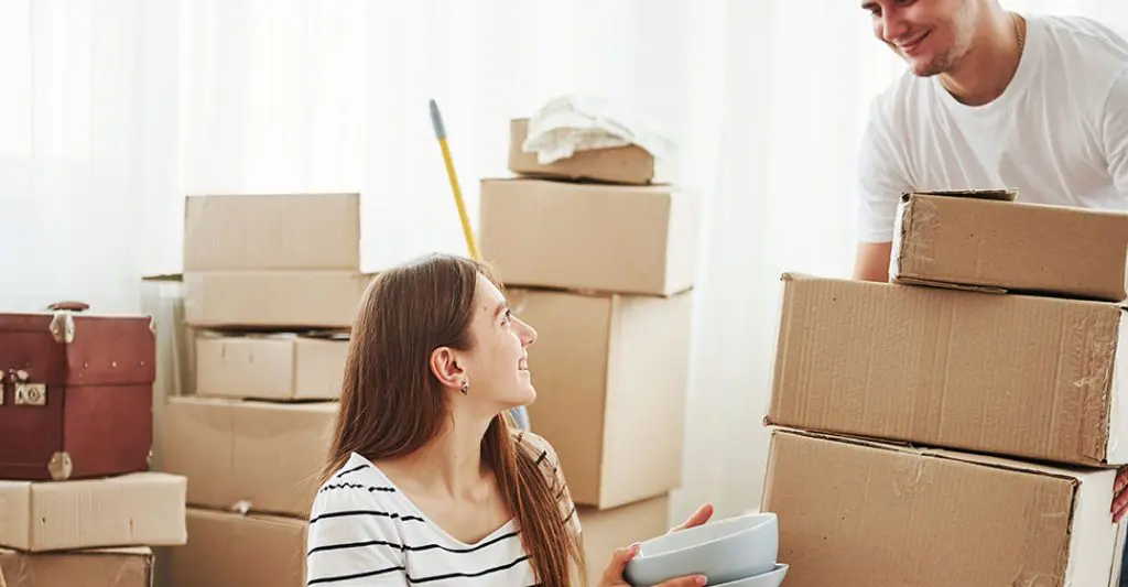 What are the standard inclusions for end of lease cleaning? 3 A smiling couple carrying cardboard boxes while moving out of their rental home.
