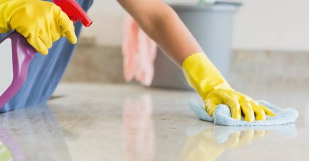 What are the standard inclusions for end of lease cleaning? 2 A close-up of a gloved hand scrubbing a floor with cleaning spray and cloth.