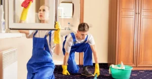 Two cleaners performing detailed carpet and window cleaning in a home for end of lease service.
