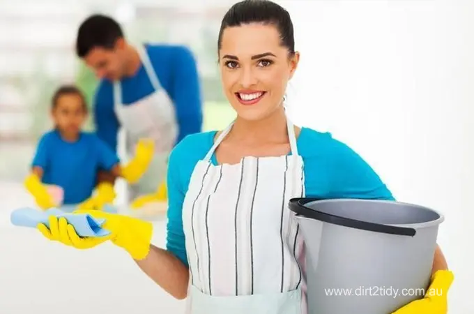 Are End of Lease Cleaning Prices more or less for different types of Homes? 2 Cheerful woman in cleaning apron and gloves, holding a bucket and cloth, with a cleaning crew in the background.