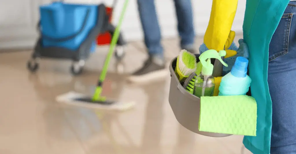 Professional end of lease cleaning cost in sydney A close-up of a cleaning professional holding a container of supplies while another mops the floor.