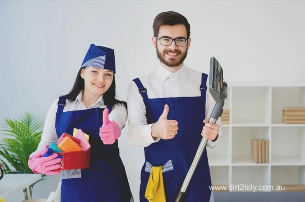 The Best end of lease cleaning Potts Point 4 Smiling male and female cleaning professionals in navy aprons giving thumbs up, holding cleaning tools and supplies – showcasing trust and quality service by Dirt2Tidy.