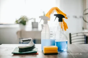 Common Mistakes to Avoid During End of Lease Cleaning in Eastern Suburbs: Insights from Dirt2Tidy 4 Cleaning sprays, gloves, and scrubber on a table in natural light.