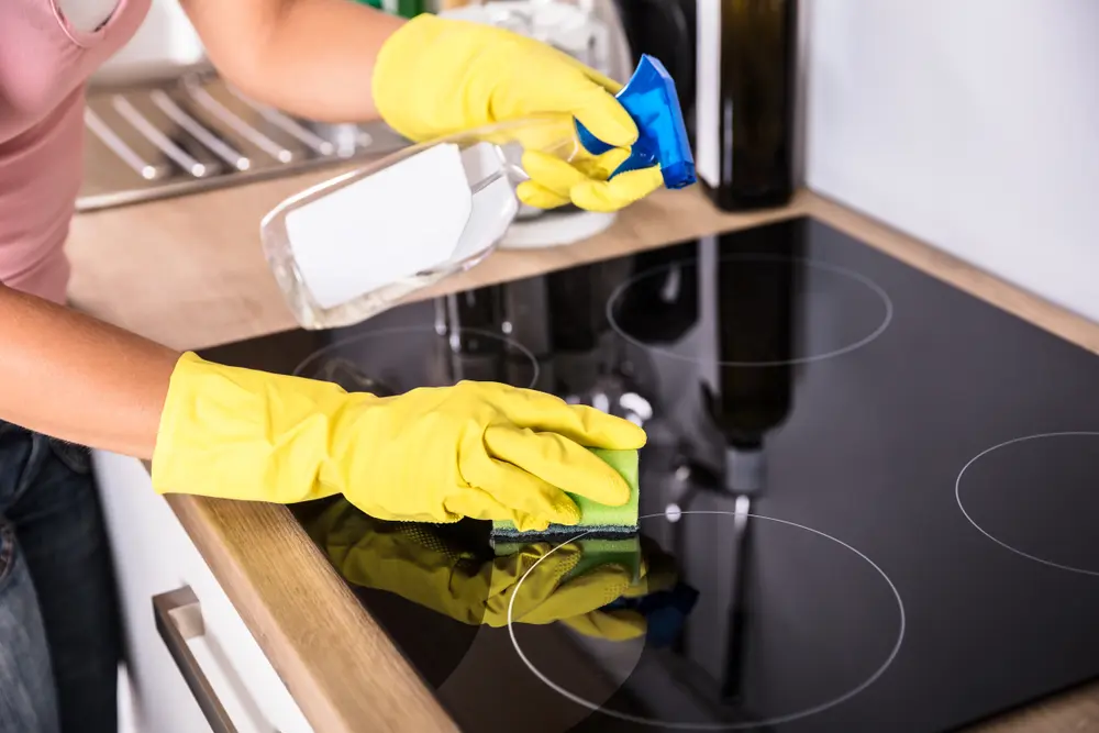 The DIY Guide to End Of Lease Cleaning 2 Person cleaning kitchen stovetop with spray and sponge.