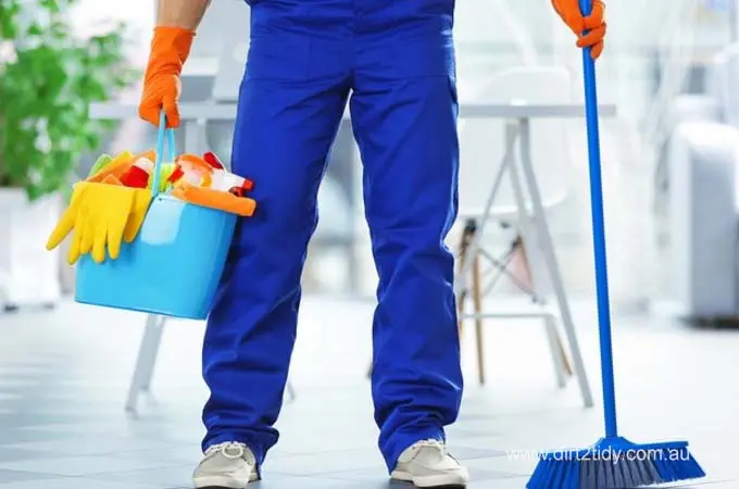 End of Lease Cleaning: How to Impress Your Australian Landlord 4 Cleaner in uniform holding a bucket of supplies and a broom.