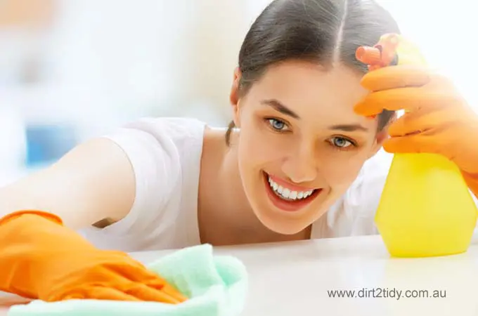 Happy woman in gloves cleaning with spray bottle and cloth.