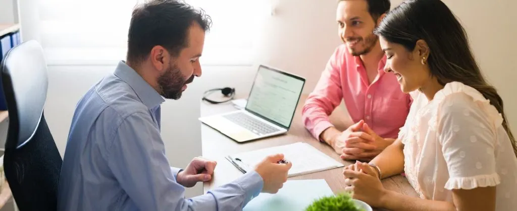 How to Handle Landlord Complaints About End of Lease Cleaning 2 A professional at a desk discussing lease documents with a smiling couple during a property consultation.