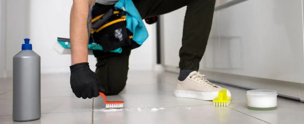 How to Handle Mold Issues During End of Lease Cleaning 2 A person in gloves using a small cleaning brush to scrub dirt from tiled flooring during detailed cleaning.